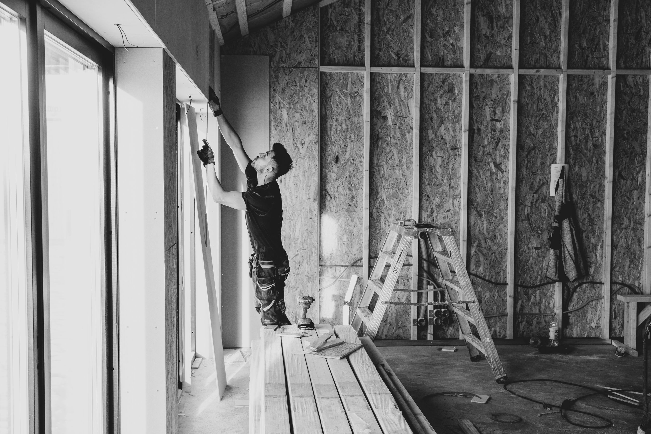 Worker installing insulation between wall studs