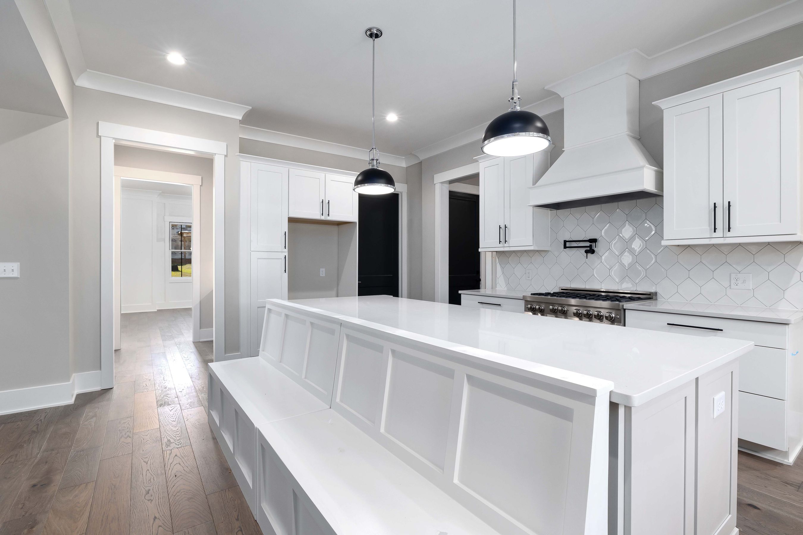 Finished white kitchen with a long island and pendant lights