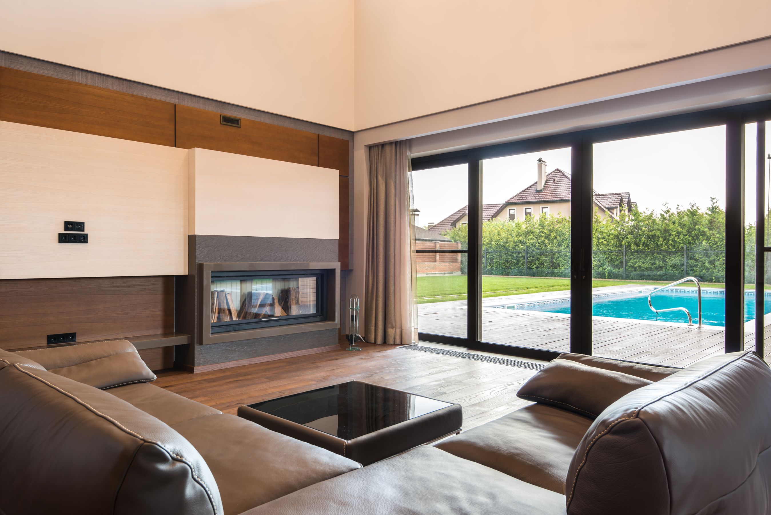 Finished living room with a fireplace and a view of the pool