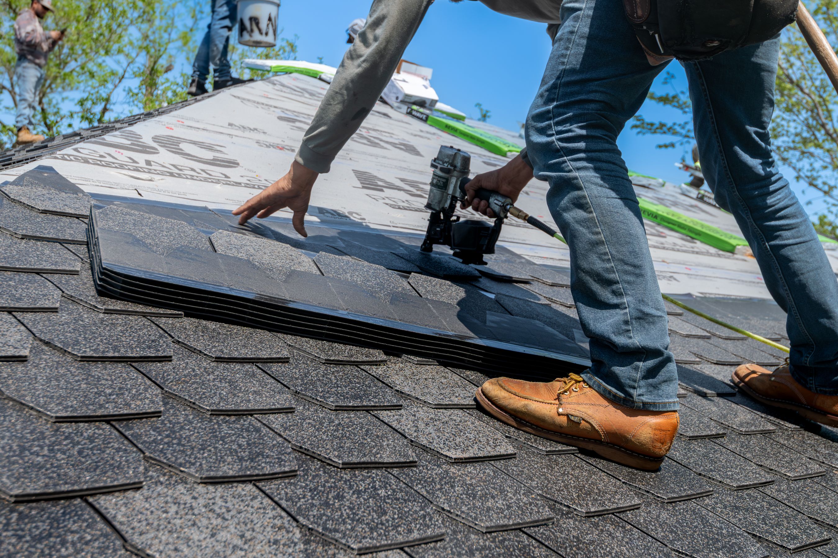 Roofer nailing shingles on a new roof