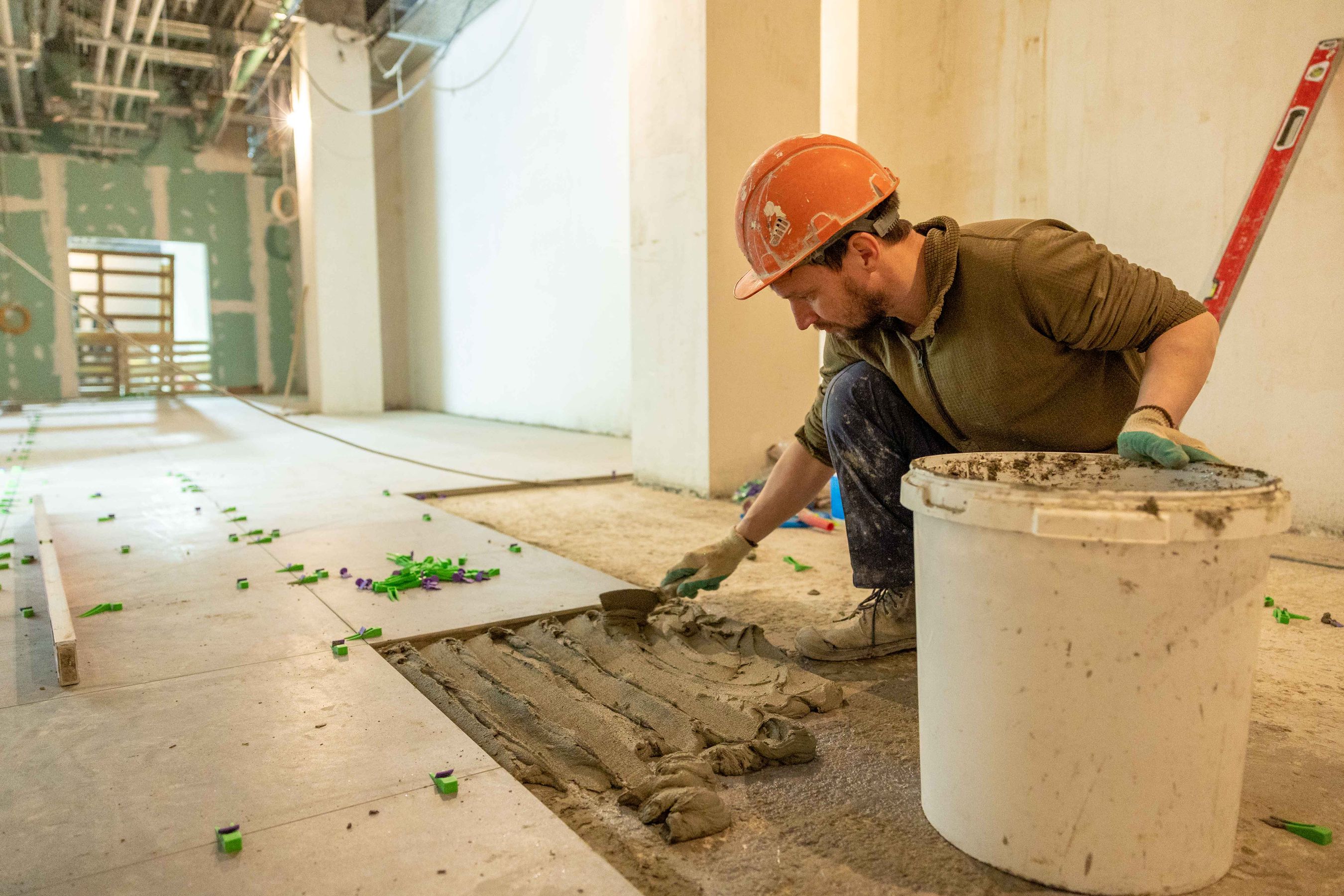 Tile setter laying floor tile in a renovation